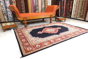 A 4 feet by 6 feet central Indian wool rug. The colours used are dark blue, beige,cream,red and brown.