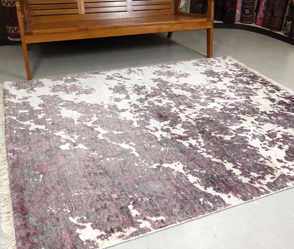 A 5 by 6 and half feet rug with an abstract design of light purple and white colours.