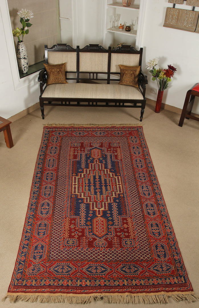 An almost 5 feet by 8 feet wool kilim, the colours include red,rust,beige and blue.