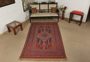 An almost 5 feet by 8 feet wool kilim, the colours include red,rust,beige and blue.