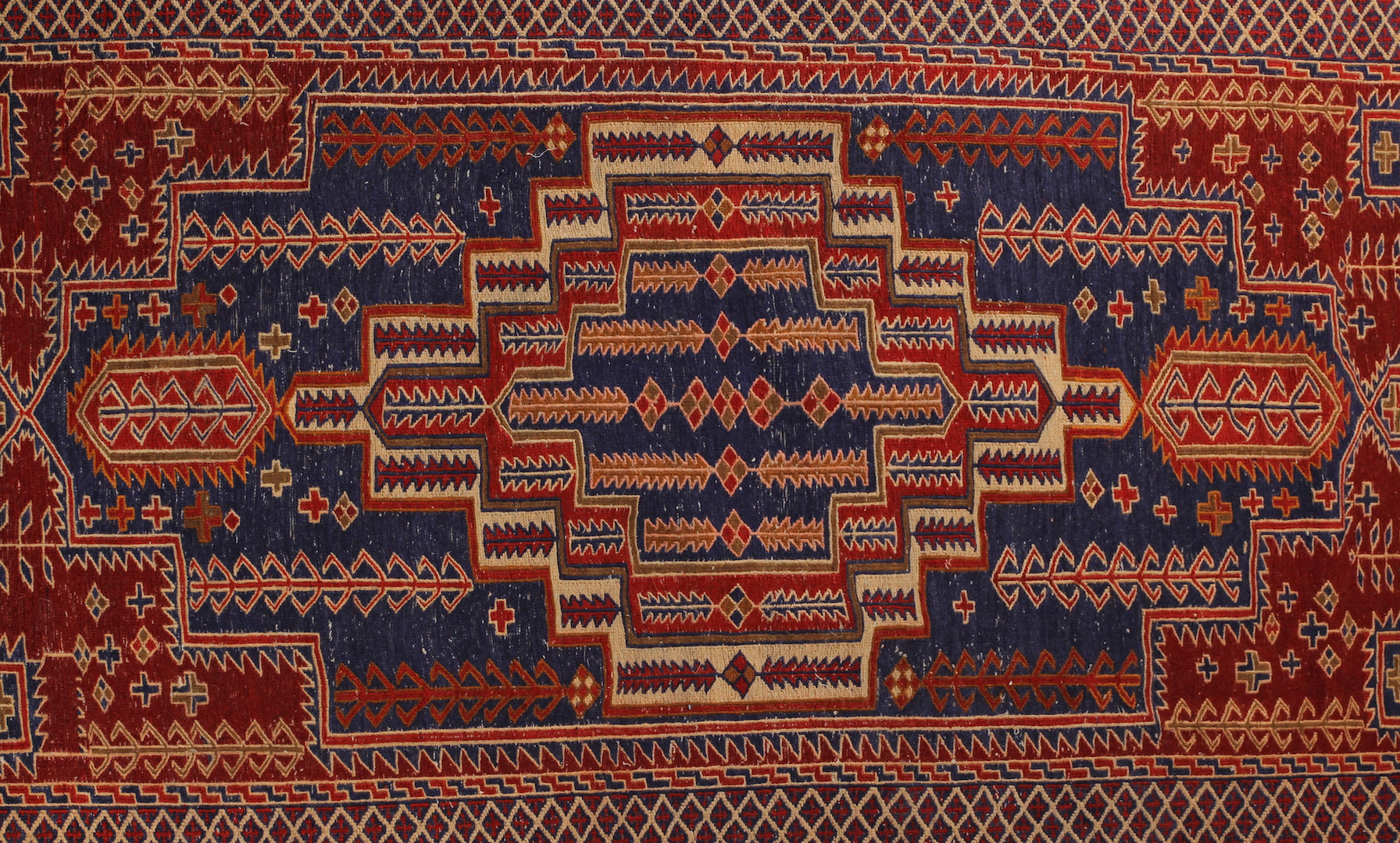 An almost 5 feet by 8 feet wool kilim, the colours include red,rust,beige and blue.