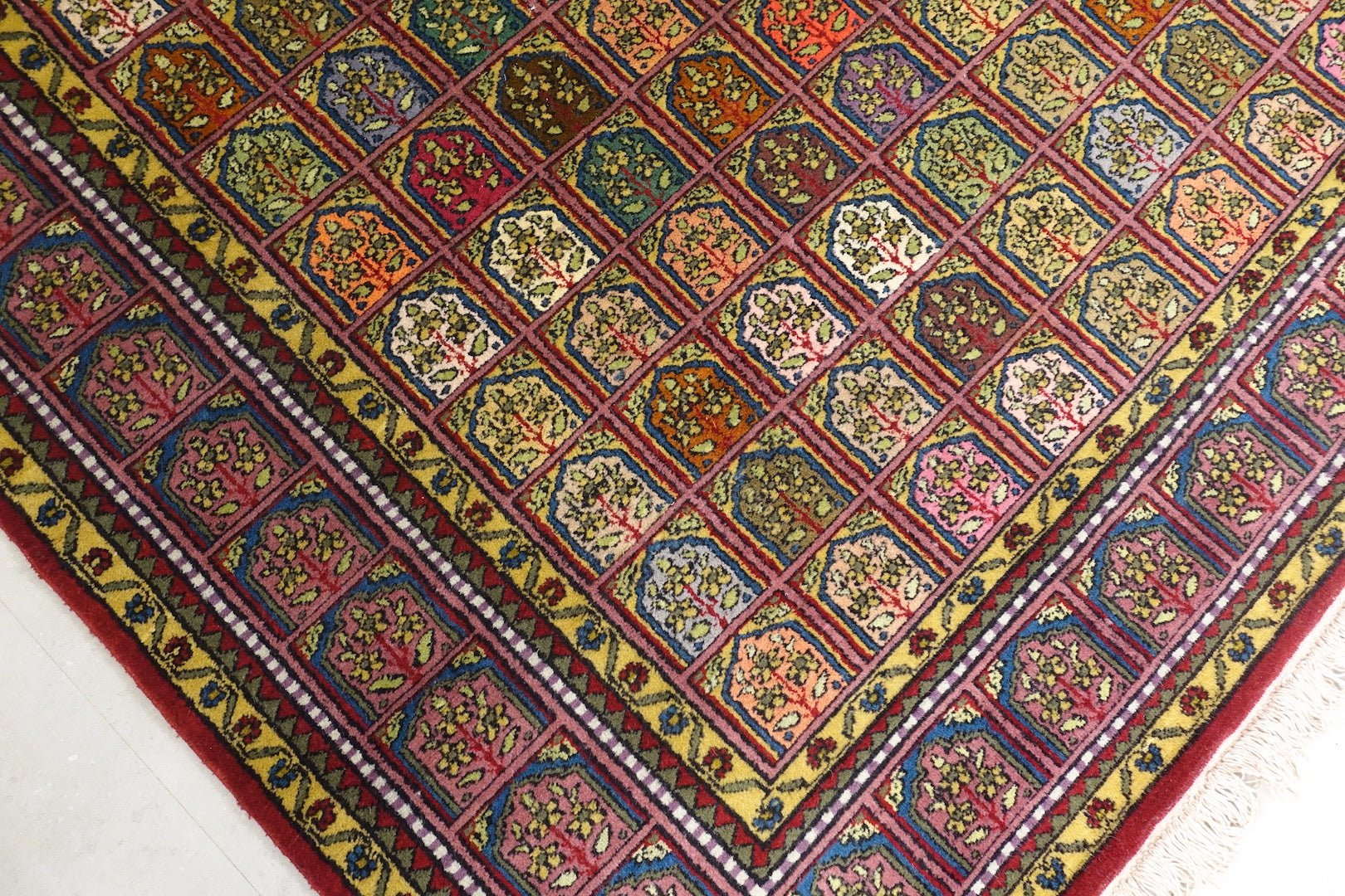 A 6 feet by 9 feet Kashmiri woolen rug, the colours used on the rug are red,orange,green, beige and blue.