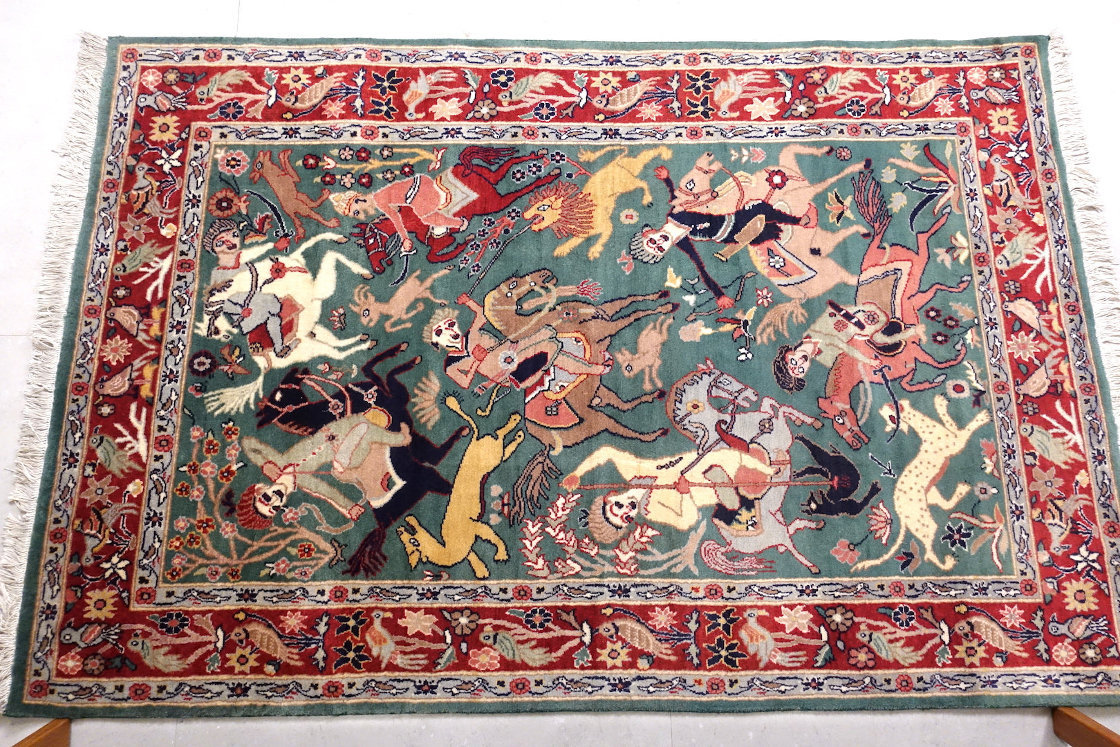 It is a 4 feet by 6 feet persian wool rug. It depicts a hunting scene and the colours used are gree,beige,red and black.