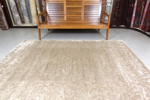 An almost 6 feet by 8 feet plain light brown rug.