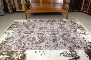 An almost 6 feet by 8 feet rug with an erased design based on the art nouveau style. The colour are dark green on a light creamish blue base.