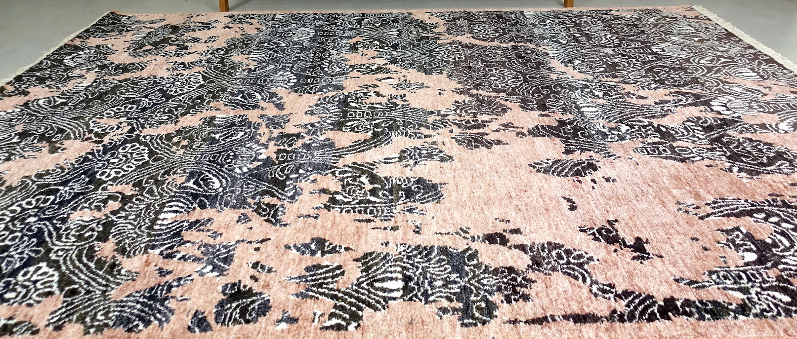 A 6 feet by 9 feet rug in pastel pink with black and white design elements.