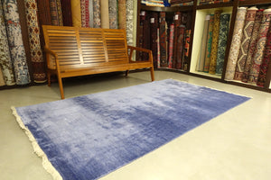 An almost 6 feet by 8.5 feet rug in plain purple.