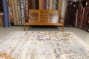 A modern rug/carpet with an abstract design. The rug is made of pastel colours. Creams, Blacks, Sea Blue and Sprinkles of brown and black. The size of the rug is 5 feet by 8 feet.