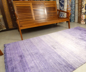 A 4.5 feet by 8 feet rug that is purple and fades inwards with white.