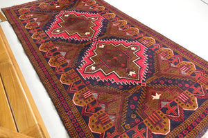 A 4 feet by 7.5 feet Balochi wool rug, the colours used are red, orange and blue.
