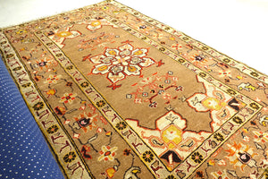 It is a 4 feet by 7 feet Indian wool rug. The colours of rust, beige, black and brick red are used on the rug.