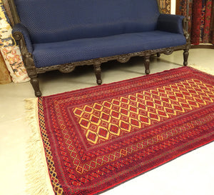 A 4 by 6 feet afghani wool rug. The colours used are red, cherry and tan.