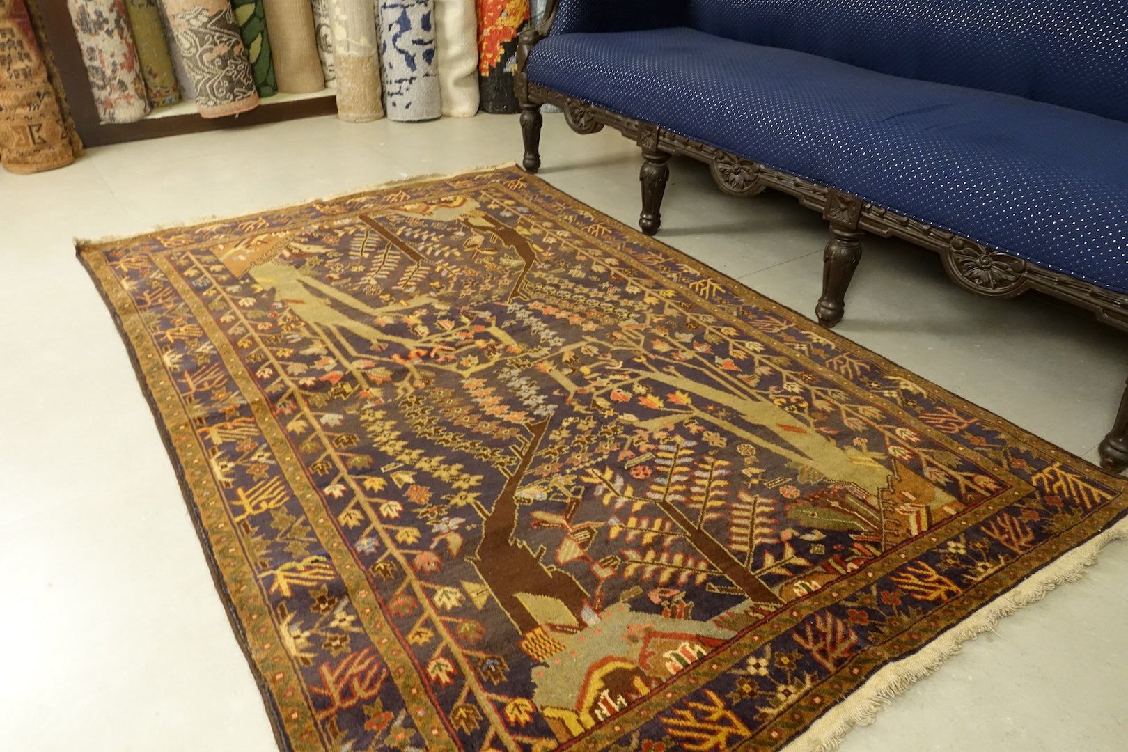 A 4 by 6 feet balochi rug. The colours primarily include beige, brick, rust, blue and green.