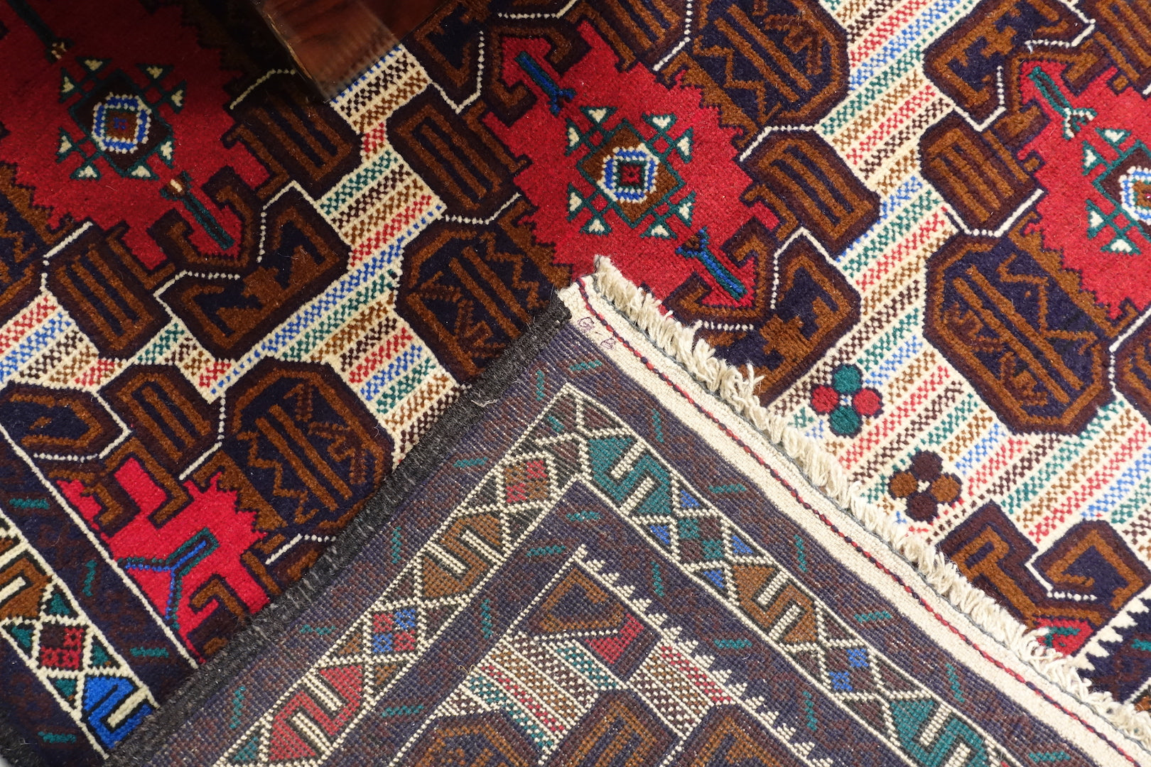 This Afghan wool rug measures 3 feet 9 inches by 6 feet 6 inches. The colours used on the rug are teal, red and beige.
