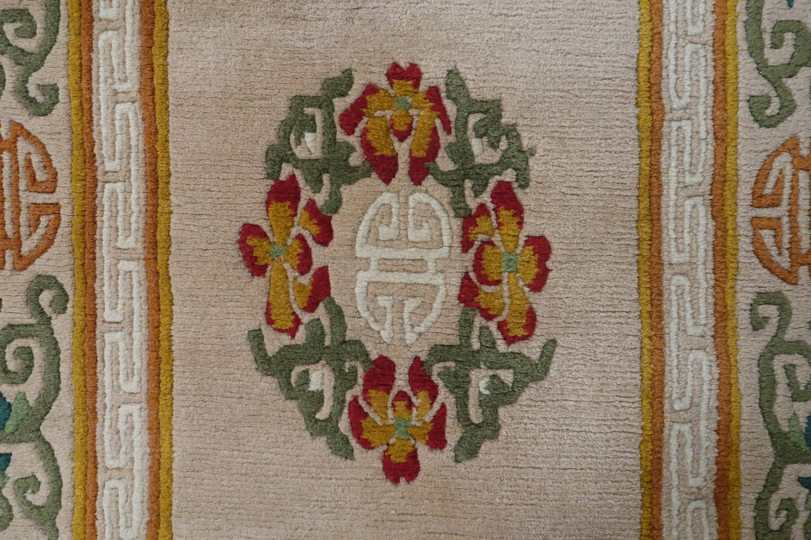 A 3 by 6 feet tibetan wool rug. The colours used are red, mustard, tan, green and white.
