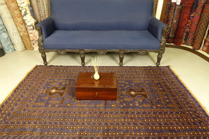 A 4 by 7 feet afghan wool rug. The colours used are typically blue, brown, beige and tan.
