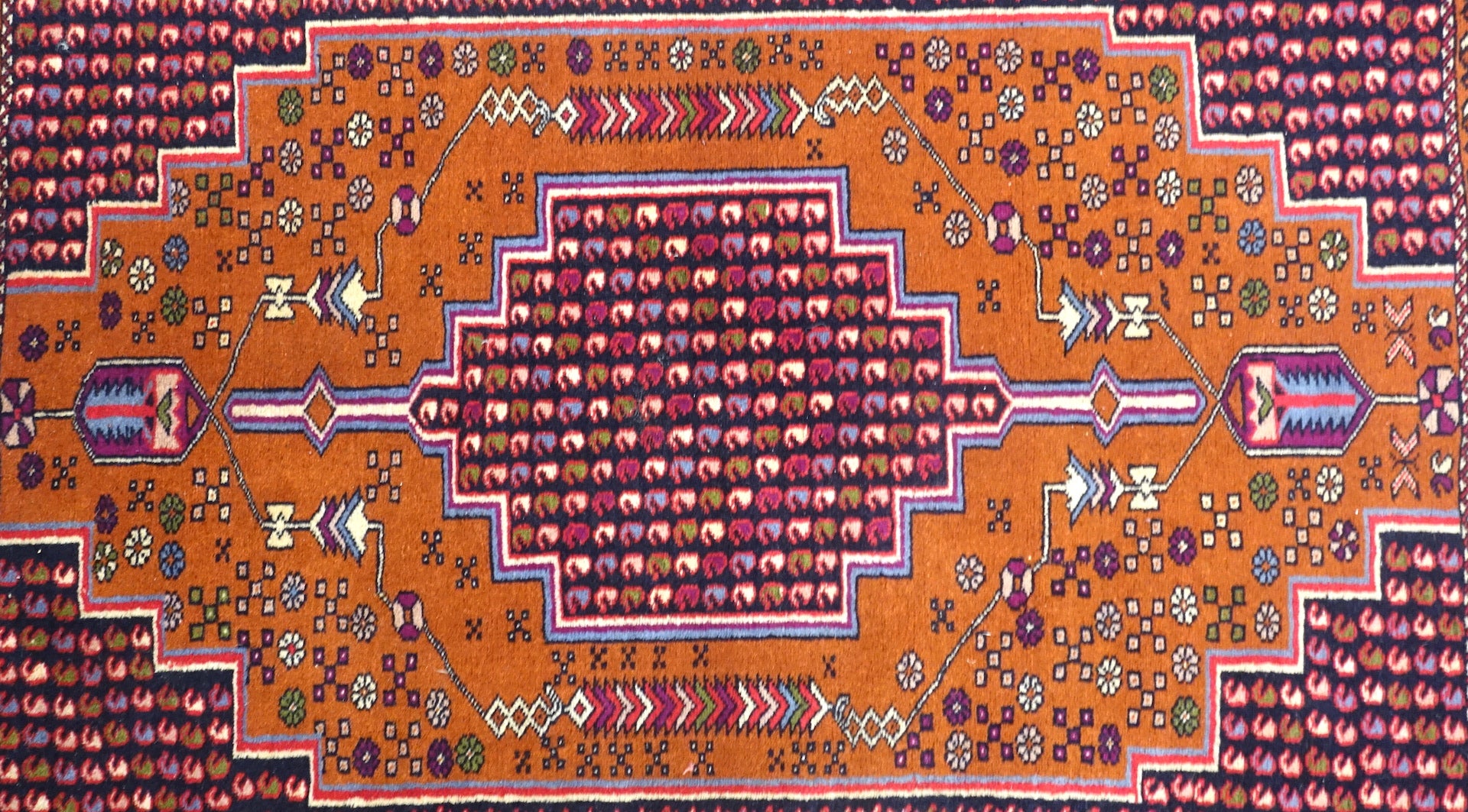 A 4 by 6 feet balochi wool rug. Shades used are primarily brick, purple, green, beige, black and cherry.