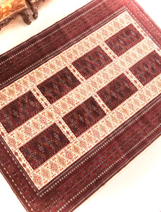 A 5 feet by 7 feet indian wool rug, the colours used are deep red, rust, blue and white.