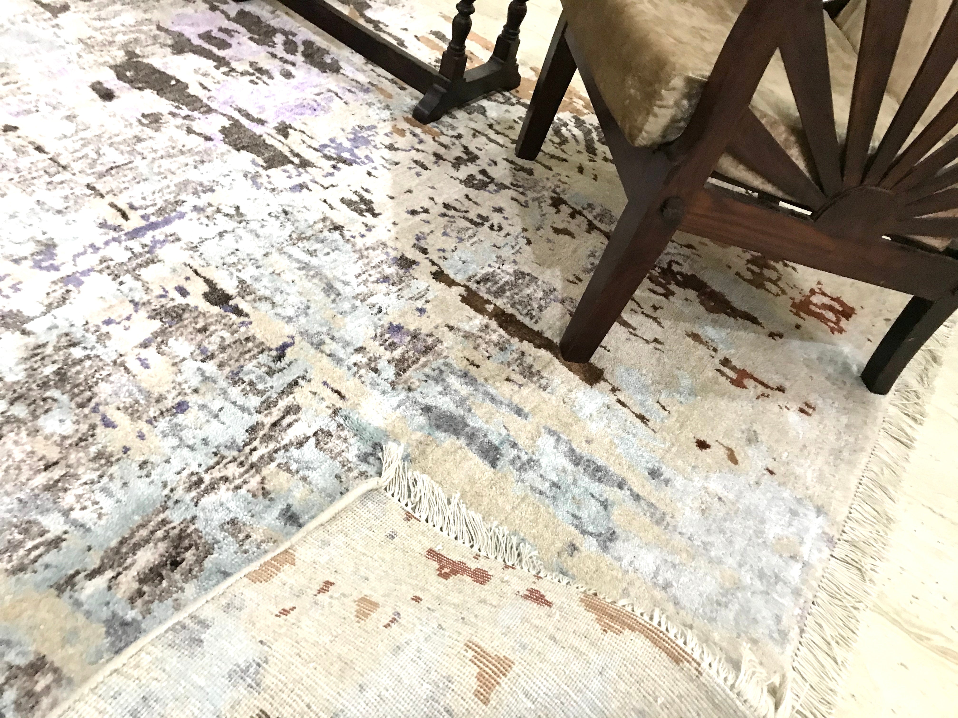 A modern rug/carpet with an abstract design. The rug is made of pastel colours. Creams, Blacks, Sea Blue and Sprinkles of brown and black. The size of the rug is 5 feet by 8 feet.
